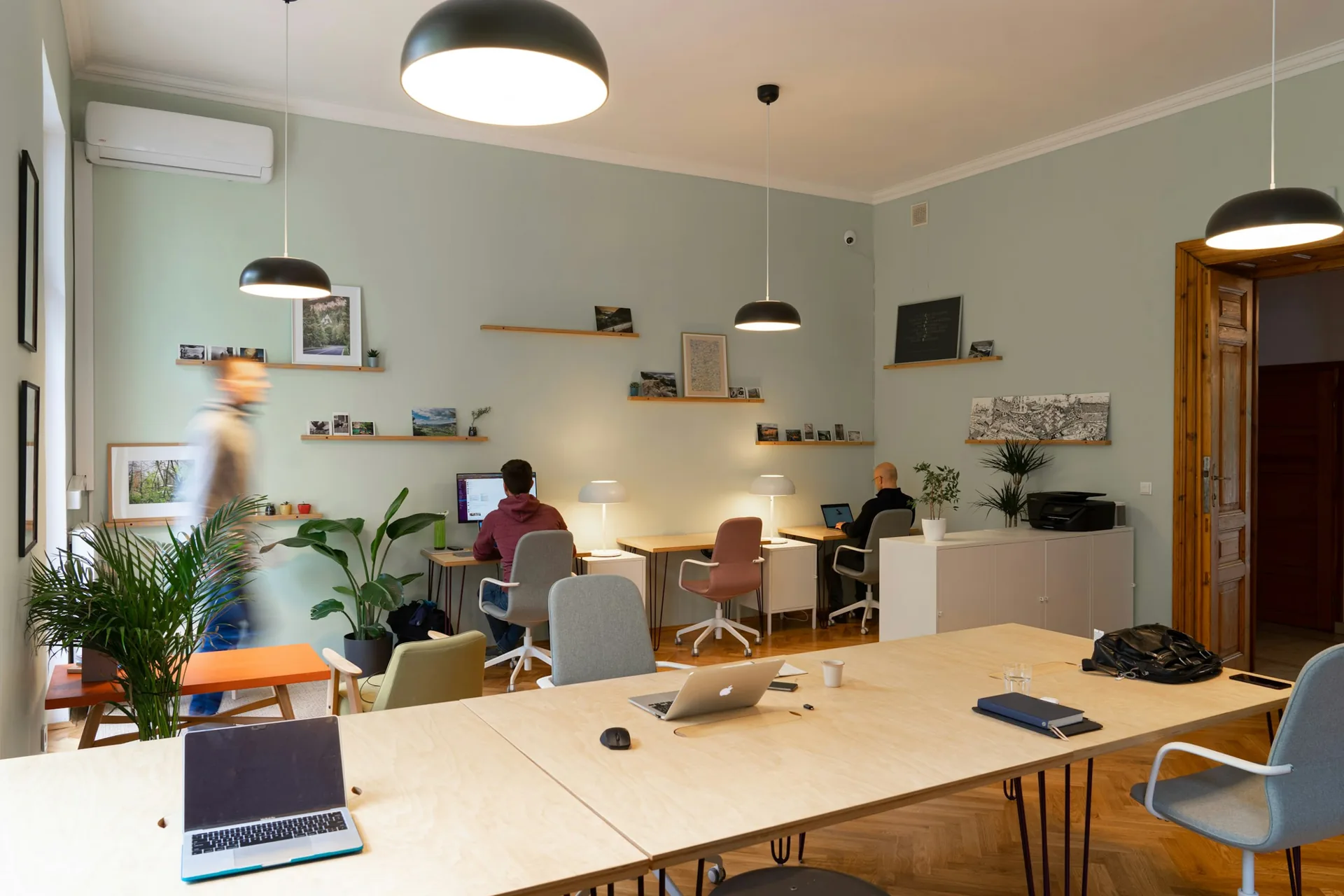 Sala de trabalho do escritório, com mesa comprida e profissionais ao fundo